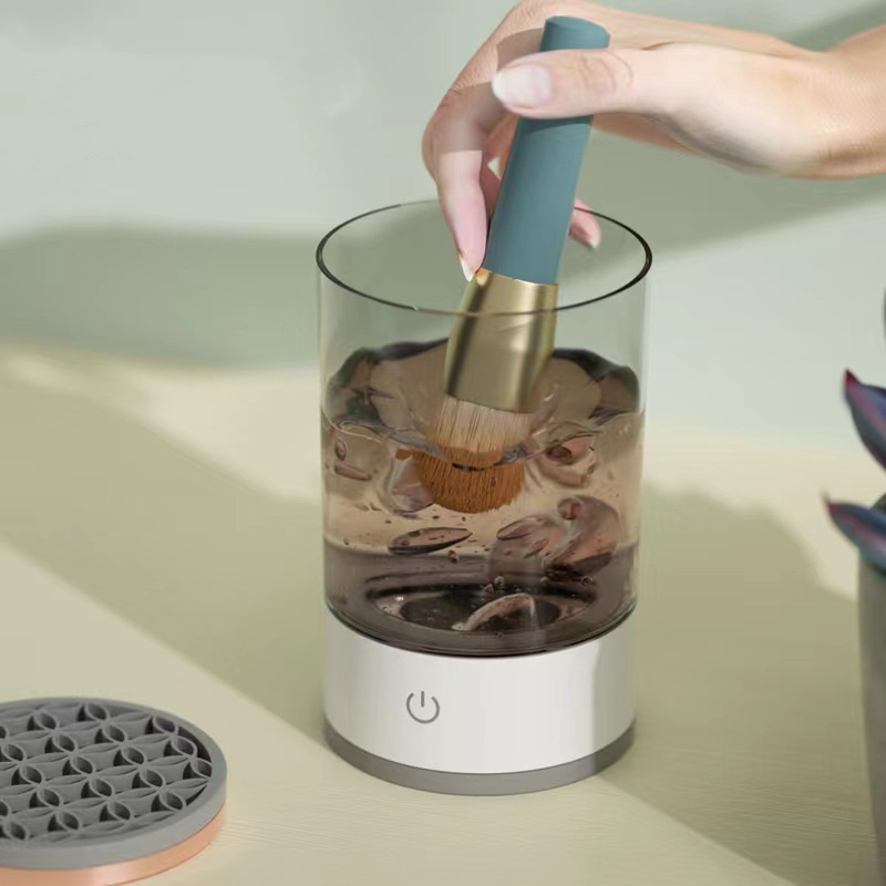 Makeup brush being deep-cleaned inside the electric cup