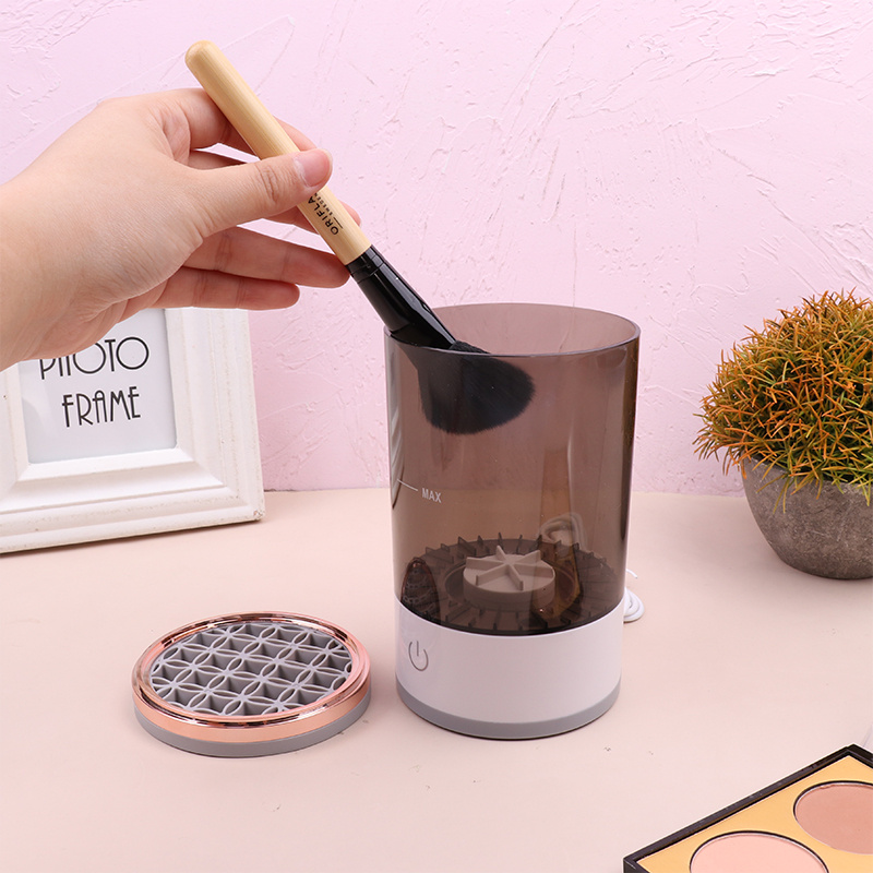 Hand placing a makeup brush into the electric cleaner